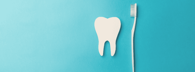 a white paper tooth and a white toothbrush with a cyan color background
